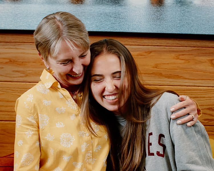 Two people sitting close together in a warmly lit room, leaning in toward each other.